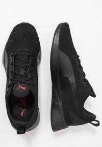 Scarpe da ginnastica nere con tomaia in rete, dettagli testurizzati, lacci piatti e suola spessa in gomma con design a righe.