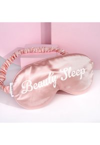 Rosa satin sovmask med ett veckat tygband, med texten "Beauty Sleep" i vit skrivstil. Mjuk, glansig textur.