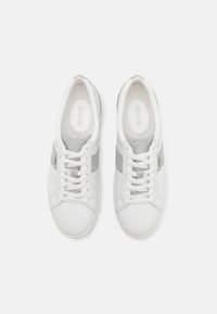 Balto odiniai sportbačiai su sidabro audinio akcentais ir baltais raišteliais, matomi iš viršaus ant šviesiai pilko fono.