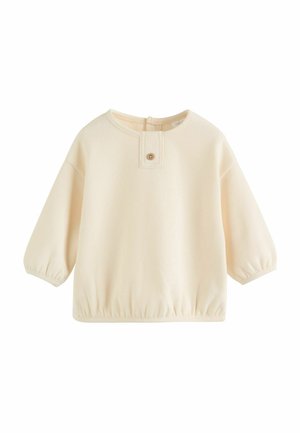 Pull-over couleur crème avec un col arrondi et un ourlet élastiqué. Comprend une patte de boutonnage et des manches froncées pour une coupe décontractée.