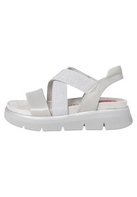 Ljust grå sandal med korskorsade remmar, ett strukturerat elastiskt band och en vadderad sula. Utrustad med en gummisula med ribbat mönster.
