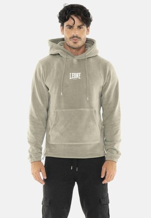 Man draagt een lichtgrijze capuchontrui met het "LEONE 1947" logo en zwarte cargobroek, staande tegen een witte achtergrond.
