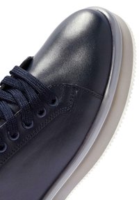 Sneaker in pelle blu scuro con punta rotonda, lacci texturizzati e suola in gomma bianca. Finitura liscia con cuciture minime e dettagli delle asole.