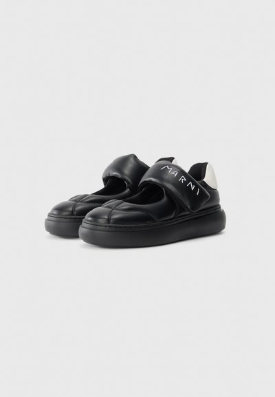 Svarta lädersneakers utan snörning med tjocka remmar märkta "MARNI" och kraftiga sulor, med vita hälaccenter.