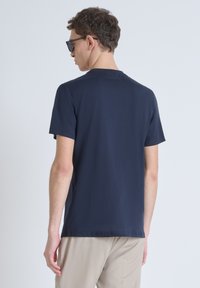 Camiseta de algodón azul marino con mangas cortas y cuello redondo, textura suave, diseño minimalista y sutil marca en la parte de atrás.