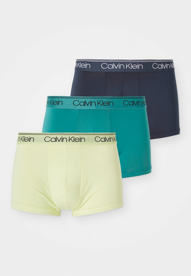 Tri parov bokseric Calvin Klein v mornarsko modri, teal in svetlo rumeni barvi. Vsak par ima kontrastni elastični pas z logotipom.