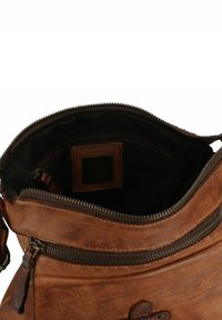 Borsa in pelle marrone con un'ampia apertura, chiusura con zip e foderatura in tessuto scuro. Presenta una piccola tasca interna e una superficie texturizzata.