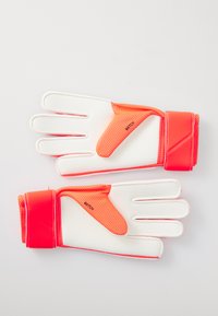 Et par med hvite og lys oransje målvaktshansker med håndleddsstropp, merket "MATCH," lagt flatt på en hvit overflate.