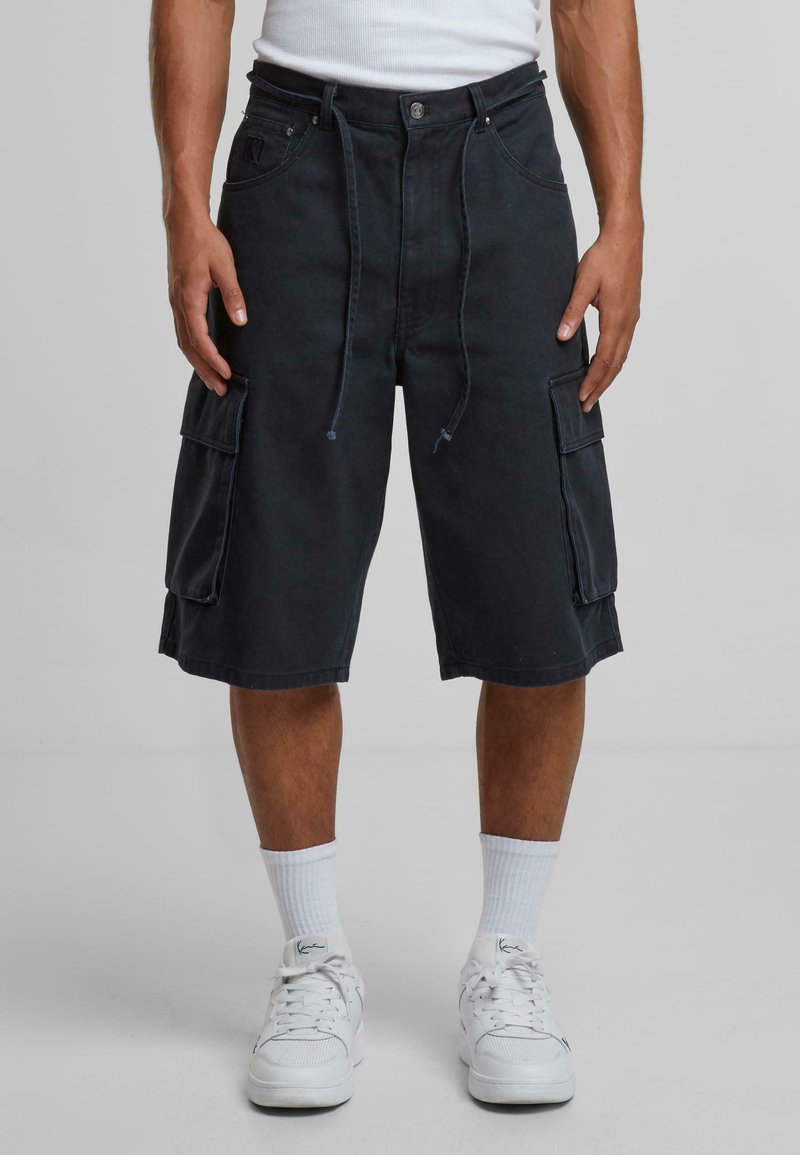 Dark navy cargo shorts made of durable fabric, featuring a relaxed fit, multiple side pockets, and drawstring closure. Worn with white sneakers.