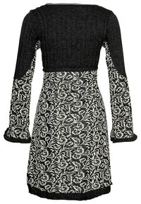 Svart klänning med ribbad liv och långa, utsvängda ärmar; har ett vitt blommönster på kjolen. Tyget inkluderar texturkontrast.
