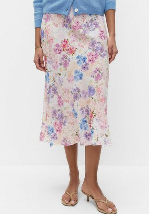 Kwiatowa spódnica midi z różowymi, fioletowymi i niebieskimi kwiatami, noszona z niebieskim kardiganem i beżowymi sandałami na obcasie na bose stopy.