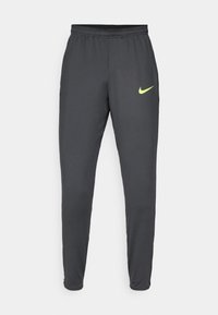 Nike atletische broek van een gladde, lichte stof. Donkergrijs met een neongele logo aan de voorkant. Elastische tailleband en taps toelopende benen.