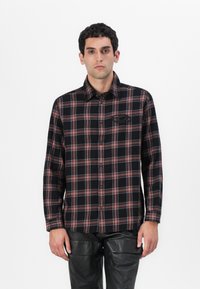 Camicia a scacchi nera e rossa con colletto button-down, maniche lunghe e taschino sul petto, realizzata in un morbido tessuto intrecciato.