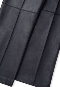 Czarne skórzane spodnie o teksturowanym wykończeniu, z przeszywanymi panelami i gładkimi krawędziami. Całościowa sylwetka jest dopasowana.