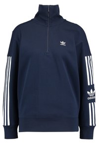 Sweatshirt zippé marine avec un col montant, accents rayés blancs sur les manches et un logo Adidas brodé sur la poitrine. Texture de tissu douce.
