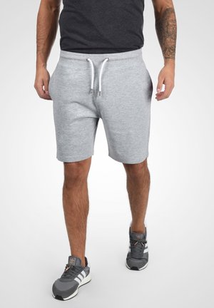 Grijze katoenen shorts met een elastische tailleband en een witte trekkoord. Bevat zijzakken en heeft een losse pasvorm, gestyled met grijze sneakers.