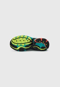 Sole of a running shoe with black, neon green, turquoise, and red rubber tread patterns on white background.
