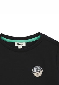 Schwarzes Baumwoll-T-Shirt mit strukturiertem Stoff, Rundhalsausschnitt mit tealfarbenem Akzent und einem gestickten Bärendesign, das eine gestreifte Mütze trägt.