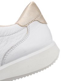 White leather sneaker heel with beige metallic accent and white textured sole with zigzag tread pattern.