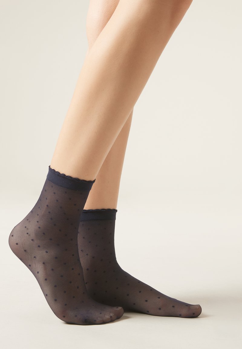 Calze alla caviglia trasparenti di un blu navy con un motivo a pois, bordo elastico ondulato e texture leggermente traslucida.