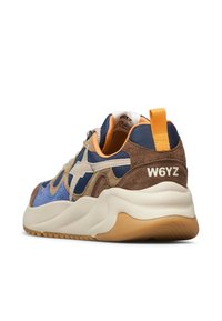 Sneaker sportivo con parte superiore in suede blu e marrone, mesh, dettagli bianchi e una spessa suola intermedia color crema. Include un gancio sul retro.