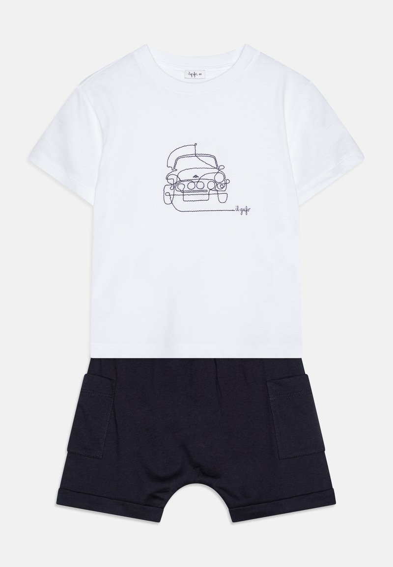 Camiseta de algodón blanca con un diseño de un coche en contorno negro, combinada con pantalones cortos de algodón azul marino con bolsillos laterales y puños enrollados.