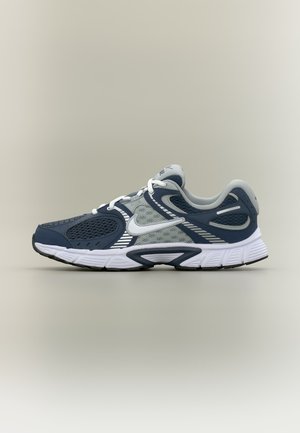 Tmavomodrá a sivá bežecká topánka Nike s bielym logo swoosh, sieťovinovými panelmi a bielou podrážkou, zobrazená zboku na neutrálnom pozadí.