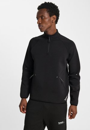 Zwarte pullover sweatshirt met een hoge kraag, kwart rits, raglanmouwen en ritszakken. Gemaakt van een getextureerde stof met een getailleerd ontwerp.