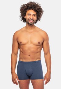 Boxer da uomo blu con motivo, realizzati in tessuto morbido, presentano una cintura rotonda e un design aderente. Il modello ha una corporatura media e capelli ricci.