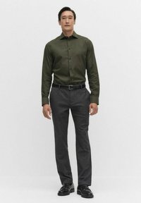 Tummanvihreä nappiolkaimia oleva paita yhdistettynä hiilenharmaisiin housuihin. Asusteena musta vyö ja kiillotetut mustat kengät täydentävät ilmeen.