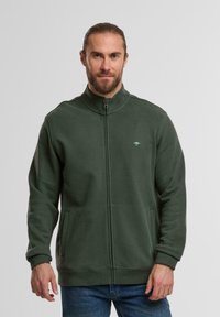 Grüner Fleece-Jacke mit Reißverschluss und hohem Kragen. Verfügt über seitliche Taschen und dezente Logodetails auf der Brust. Weicher, strukturiert Stoff.