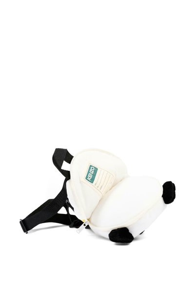 Sac à dos blanc en peluche en forme de panda avec des bretelles noires et une étiquette nominative sur le devant, posé sur le côté sur un fond blanc.