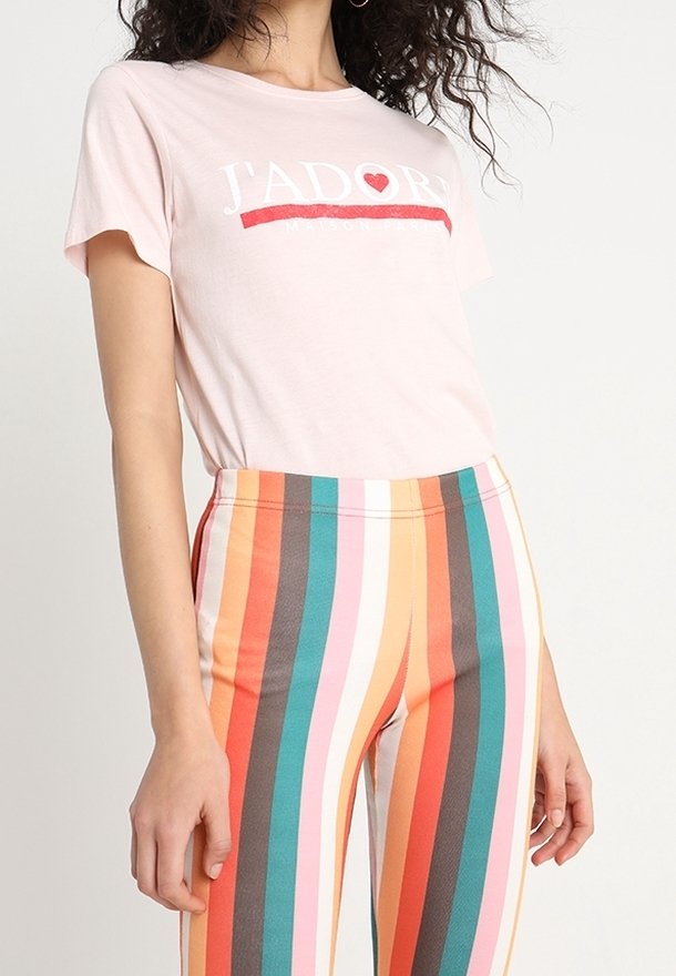 Camiseta corta de manga corta en rosa claro con texto blanco "J'ADORE" y detalles rojos, combinada con leggings a rayas multicolores en naranja, azul verdoso y marrón.