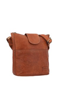 Rjav usnjen crossbody nahrbtnik z zapiranjem na pokrov, nastavljivim pasom, sprednjim žepom na zadrgo in vidnimi šivi. Teksture površine.