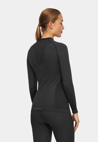 Czarna, dopasowana koszulka termiczna z długim rękawem, wykonana z elastycznego materiału, z teksturowanym panelem i prążkowanym wzorem wzdłuż pleców.