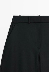 Zwarte broek met een platte voorkant, riemlussen, zijzakken en een soepele, op maat gemaakte ontwerp. De stof ziet er slank en kreukbestendig uit.