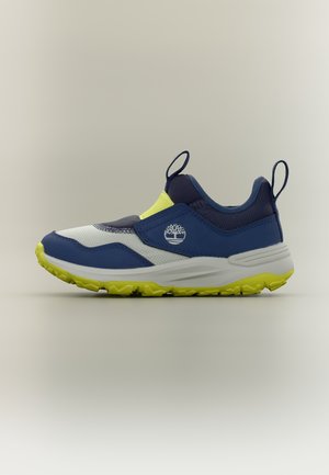 Chaussure de sport sans lacets bleue, blanche et jaune avec logo Timberland et languettes de traction sur le talon et la languette, présentée sur un fond neutre.