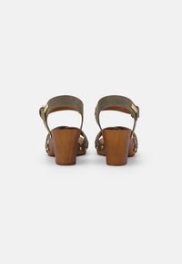 Sandales à talons bruns avec des brides en daim vert olive, dos ouvert, accents en métal doré et talons en bois.