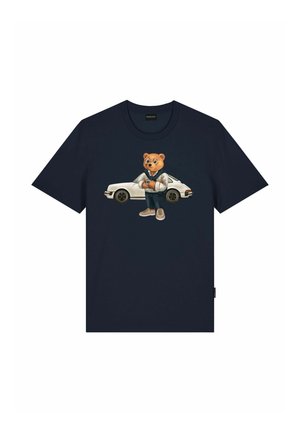 T-shirt bleu marine avec un graphisme d'un ours portant des lunettes et des vêtements décontractés, debout devant une voiture de sport vintage blanche.