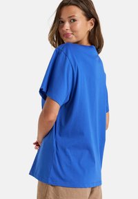Camiseta de algodón azul con un corte relajado, mangas cortas y un escote redondo. La tela parece suave, sin patrones o acentos visibles.