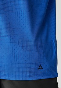 Blå sportsbluse med struktureret mønster og sorte geometriske linjer, med et lille sort logo ved kanten og korte ærmer.