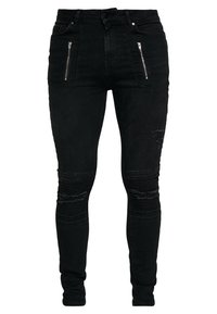 Jeans skinny de mezclilla negra con cintura alta, dos bolsillos frontales con cremallera, detalles desgastados en las rodillas y ribetes en los muslos.