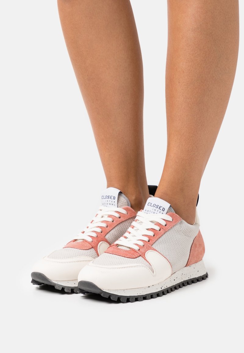 Baskets avec une tige en mesh composée de panneaux blancs, roses et gris, des lacets blancs, un logo sur la languette et une semelle noire texturée.