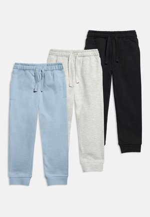 Tre paia di pantaloni jogger con vita elasticizzata e coulisse in azzurro chiaro, grigio chiaro e nero su sfondo bianco.