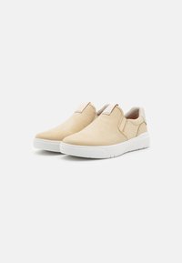 Béžové slip-on topánky vyrobené z semišu s hladkým povrchom, bielou gumovou podrážkou a minimalistickým dizajnom. Obsahujú elastické bočné panely a pútko na päte.