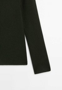 Manche longue en tricot noir de pull et ourlet latéral visible sur fond blanc.
