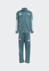 Teal trackkari, jossa on valkoiset raidat, liikuntatakki vetoketjulla ja korkealla kauluksella sekä housut. Molemmissa osissa on punainen "MARVEL"-logo ja Adidas-logo.