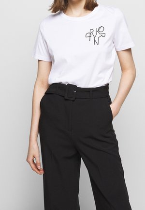 Wit katoenen T-shirt met korte mouwen, voorzien van een zwarte abstracte afbeelding op de linkerborst, gecombineerd met zwart, hooggetailleerde broek.