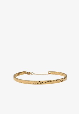 Dunne gesmede gouden chokerketting met een klein veiligheidskettingetje en sluiting op een witte achtergrond.
