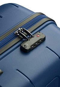 Valigia rigida blu con superficie texturizzata, cerniera nera e lucchetto approvato dalla TSA con accenti rossi. Include hardware in argento e caratteristiche di sicurezza.